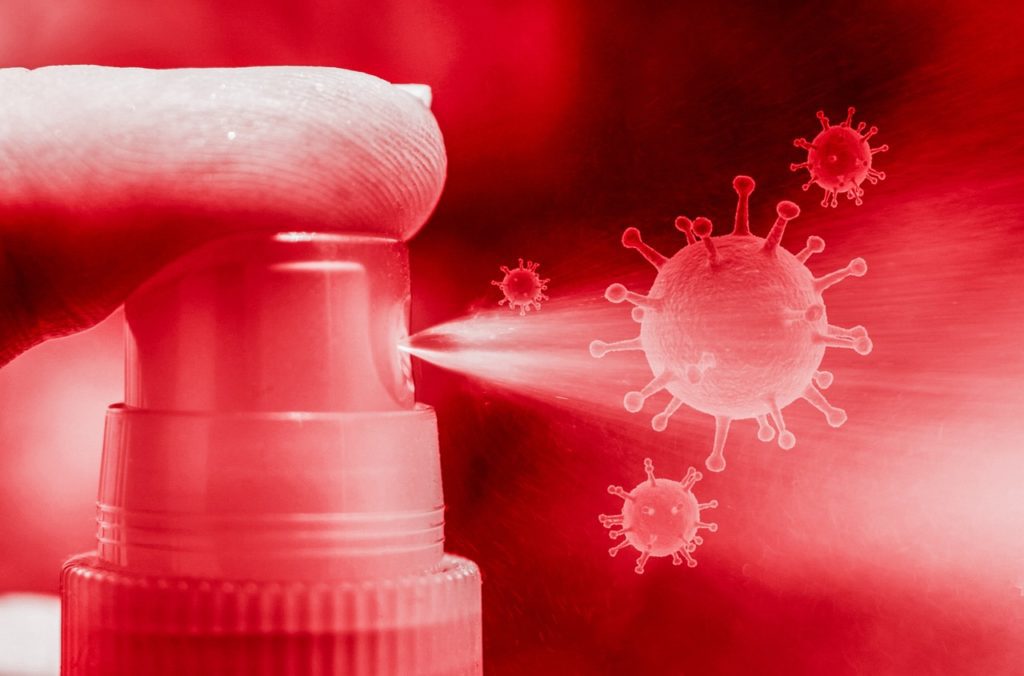 Finger pushing down on spray bottle attacking animated virus cells in the air. 